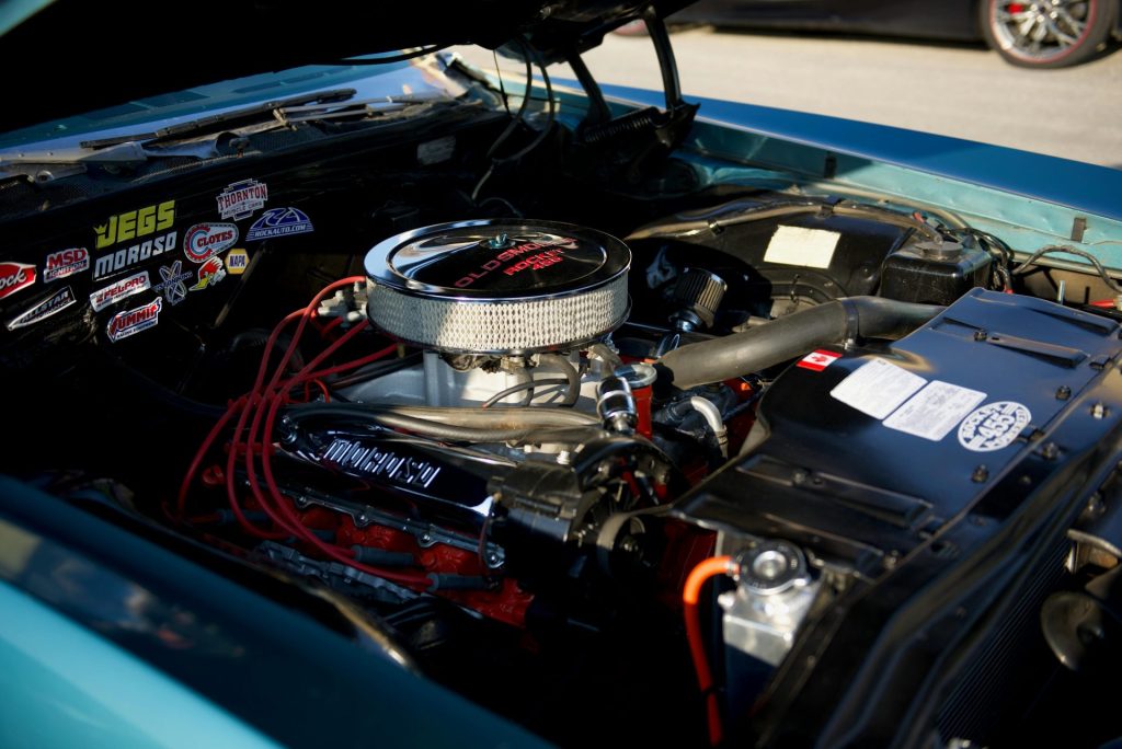 Detailansicht eines Oldtimermotors mit Tuningteilen und verschiedenen Markenaufklebern.